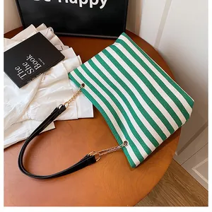 Detailed shot of green and white striped canvas tote with metal chain leather strap