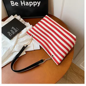 Detail of red and white striped tote bag with black leather and gold chain straps