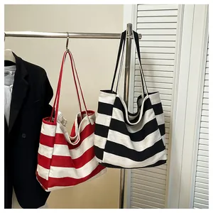 Detailed view of red and black striped canvas tote bags hanging on a modern rack