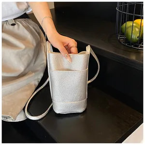 Detail of silver textured leather phone bag on dark wood table in lifestyle setting