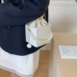 Detail of white bucket bag with 3D embossed dots and elegant pearl carry handle