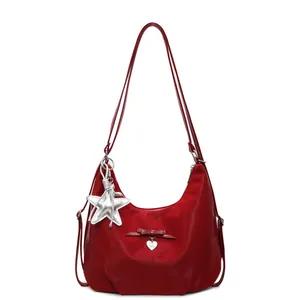 Red hobo crossbody bag with bow detail and silver star charm in minimalist design