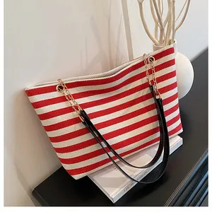 Detail of red and white striped tote bag with elegant gold chain and leather strap