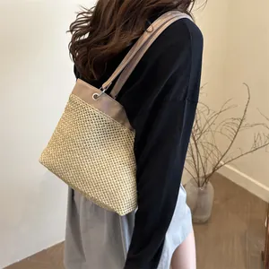 Straw tote bag with khaki leather straps and silver eyelets shown on a model