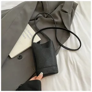 Detail of black pebbled leather texture on a minimalist mini crossbody bucket bag
