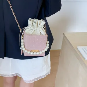 Pink textured bucket bag with pearl handle, metal chain, and drawstring lining for women