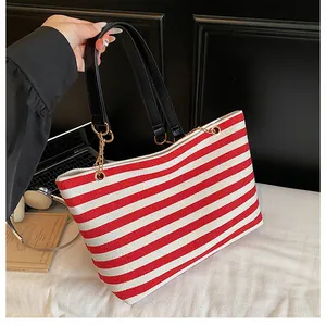 Detailed shot of red striped canvas tote with black leather straps and gold chain links