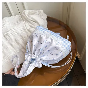 Detail of floral drawstring bucket bag with blue plaid patterns and lace trim
