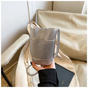 Detail of silver pebble grain bucket bag with metallic finish and slender shoulder strap