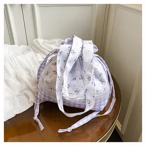 Detail view of purple gingham drawstring bag with floral patchwork and white lace trim