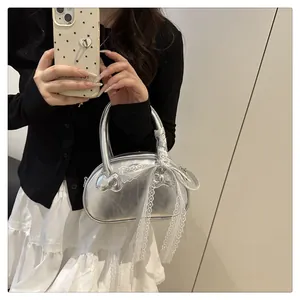 Detailed macro shot of a silver metallic mini handbag featuring a white lace bow detail