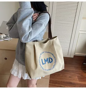 Detail view of beige canvas tote with blue embroidered poem and dark brown handle