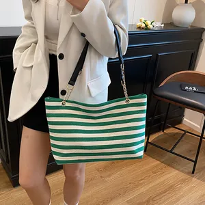 Green and white striped canvas tote bag with leather chain strap in modern interior