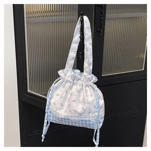 Detail of floral and blue checkered drawstring bucket bag with white lace trim on cabinet