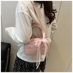 Detail of pink handheld bag featuring embossed cat design and decorative lace ribbon