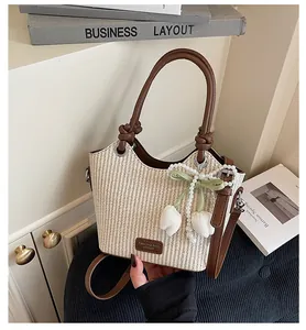 Detalle de bolso de paja trenzada con asas de cuero marrón y un colgante de tulipán de perlas