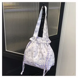 Close-up of floral drawstring bucket bag with lace details and gingham base texture
