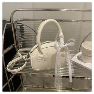Detail of cream white boston bag with bow embossing and lace ribbon on the handle
