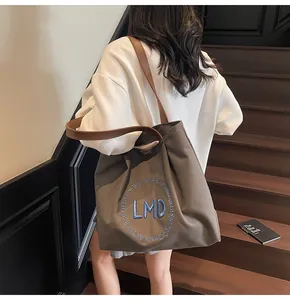 Deep olive canvas tote bag with leather straps and embroidery shown in use on stairs