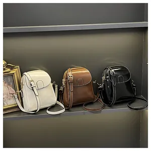 Detailed view of small square crossbody bags in white, brown, and black leather with stitching