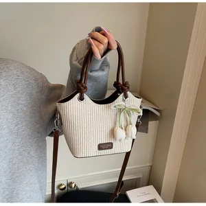 Detalle de bolso cubo de paja con asa de cuero, colgante de tulipán y perlas finas