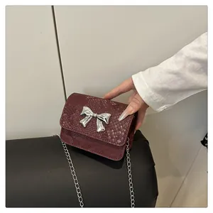 Macro view of burgundy snakeskin leather mini bag with silver metal bow detail