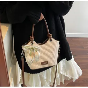 Detalle del bolso tipo cubo de paja tejida con asas de cuero y dijes de tulipanes