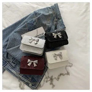 Flat lay of mini snakeskin bags in four colors with silver bow buckles and metal chains