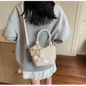 Detalle del bolso de paja beige con lazo de perlas, colgante de tulipa y correas de cuero