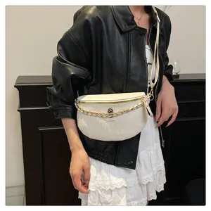 Detail of white embossed leather crossbody bag with skull charm and gold chain