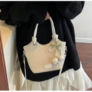 Detalle del bolso de paja con asas de cuero blanco y colgante de perlas de tulipán