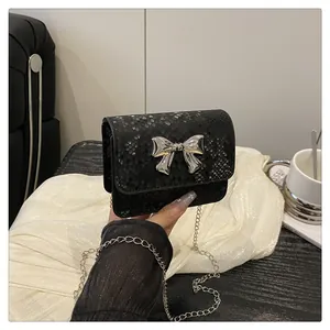 Close-up of black snake-pattern mini bag with silver bow accent and chain strap