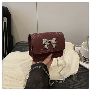 Close-up of wine red snakeskin texture mini bag with silver bow buckle and metal chain
