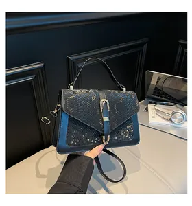 Detail of crossbody bag featuring snakeskin texture flap and gold buckle on black leather