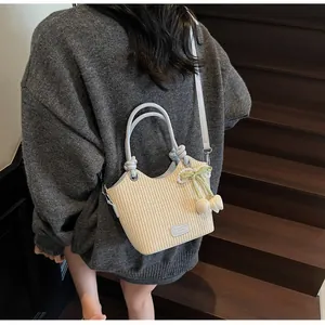 Detalle de bolso saco de paja con asa de cuero azul y colgante de flor en escalera