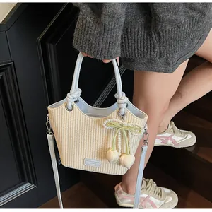 Detalle de bolso saco de paja beige con ribete de cuero azul claro y colgante de flor
