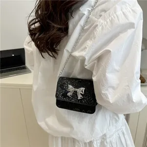 Black snakeskin textured crossbody bag with silver bow accent and elegant chain strap