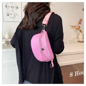 Close-up of pink embossed leather chest bag with skull pattern and gold metal chain strap