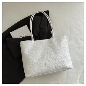 Gros plan sur la texture en cuir tressé et l'étiquette mode d'un grand sac cabas blanc