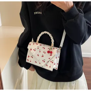 Détail du sac à bandoulière blanc imprimé cerises avec poignée tressée et charm cerise