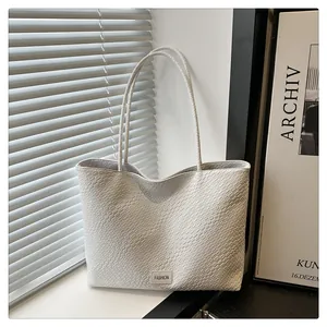 Détails d'un sac cabas blanc à texture tressée avec fines lanières et logo fashion