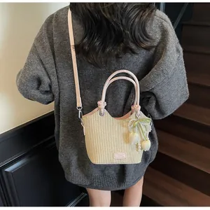 Detalle del bolso tipo saco de paja con asa de cuero rosa y colgante de perla y tulipán