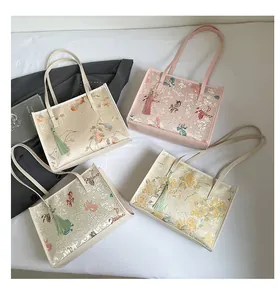 Detail of four Chinese style embroidered tote bags with tassels and long leather straps