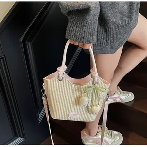 Detalle de bolso saco de paja con ribete de cuero rosa y colgante de perla tulipa