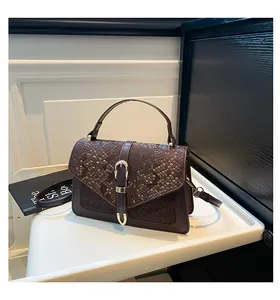 Detail of dark brown handbag showing snake pattern texture and golden horseshoe buckle
