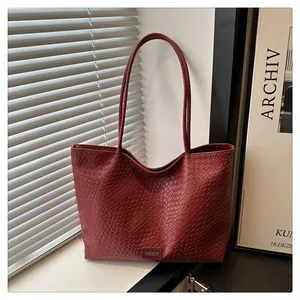 Détail de la texture tressée et de l'étiquette sur un grand sac cabas bordeaux