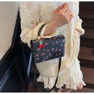 Détail d'un sac à main noir à motif cerises porté par un mannequin en scène