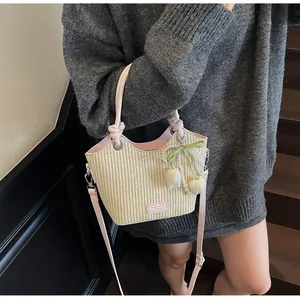 Detalle de bolso cubo de paja con asas de cuero rosa y un delicado colgante de perla tulipa