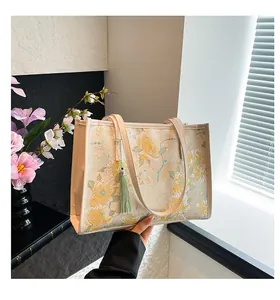 Detailed close-up of floral embroidery texture and green tassel on the elegant tote bag
