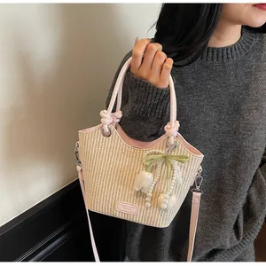 Detalle de bolso saco de paja con ribete de cuero rosa y colgantes de tulipán